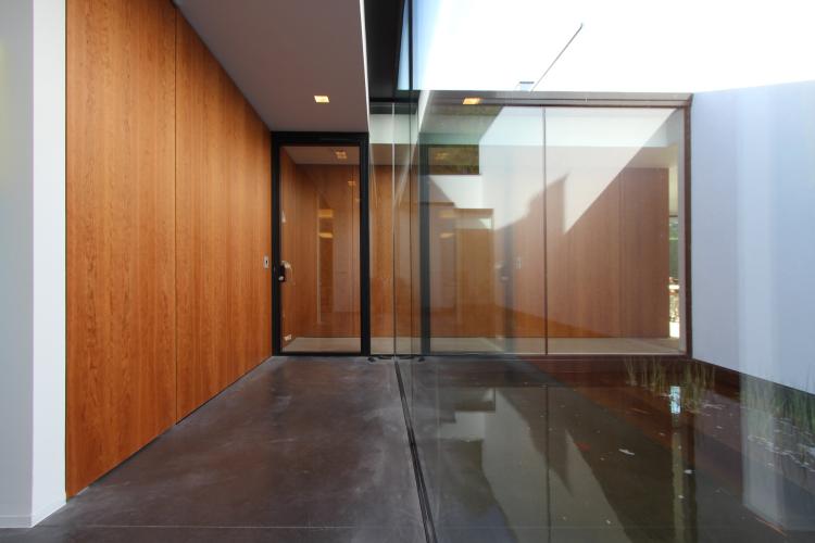 Houten accentmuur in hal naast vijver voor Sheci architecten